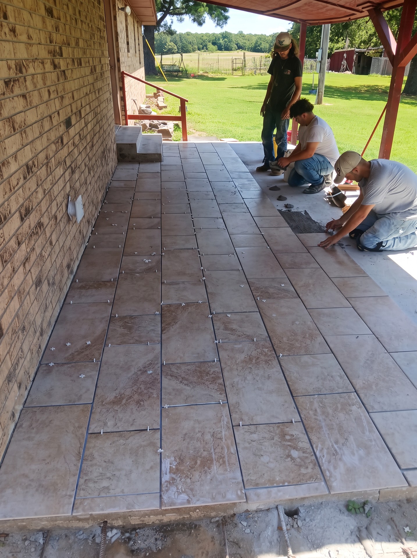 Crew installing tile on a covered porch