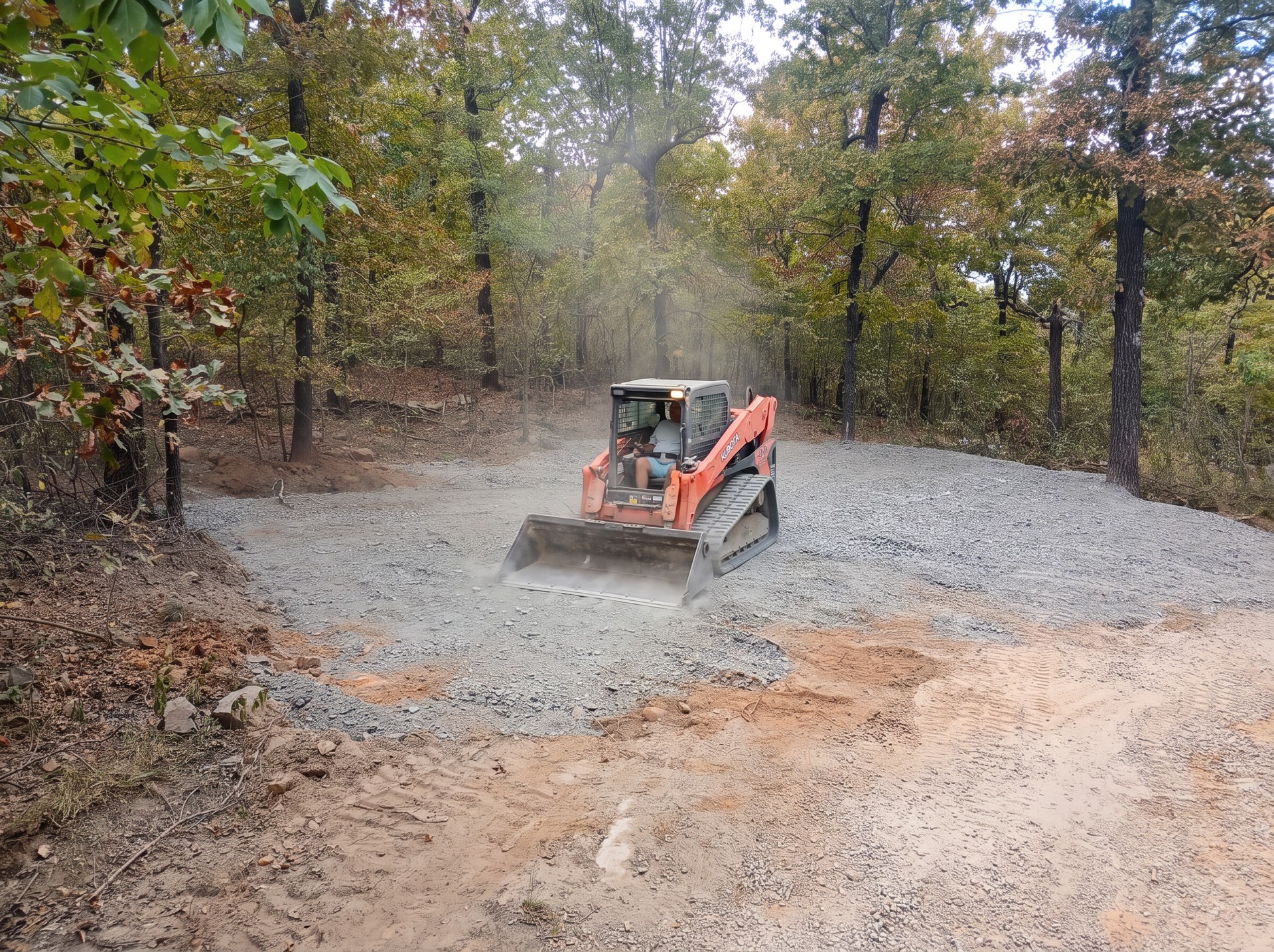Skid steer spreading gravel on a wooded property