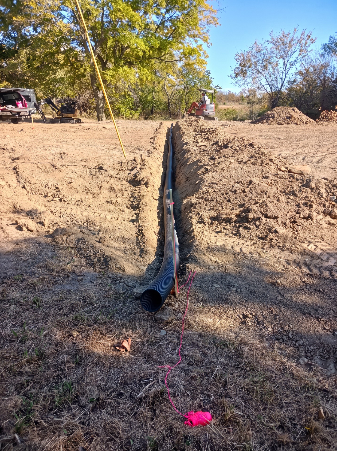 Excavated trench with pipe and a mini excavator